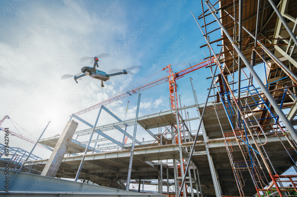 AdobeStock_373427661_Preview Eine Drohne fliegt über eine Großbaustelle