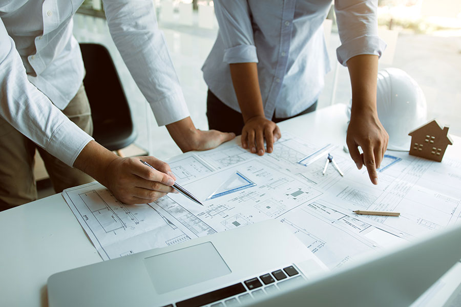 leistungen-1 Bauingenieure stehen gemeinsam am Schreibtisch und besprechen ein Projekt.